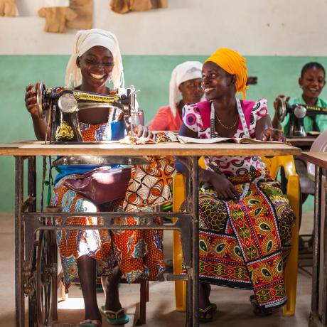 Two women working at sewing machines and smiling